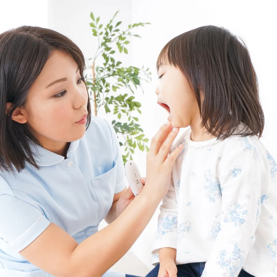 口を開けた子どもの様子を確認するスタッフ